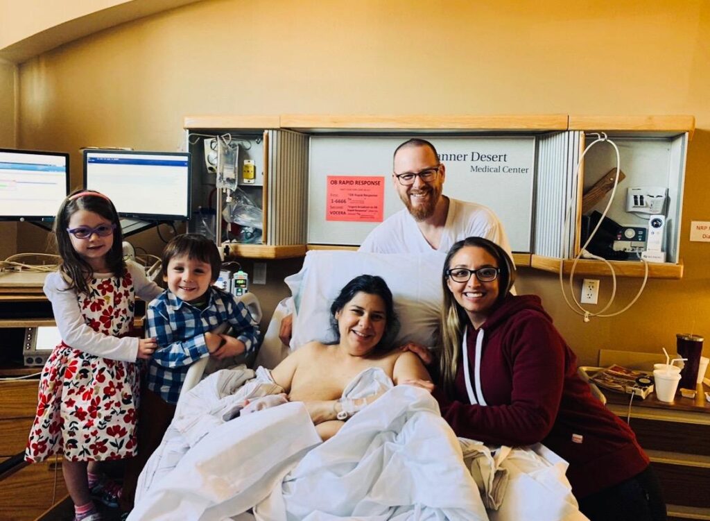 A tri-peat client with her three kids, partner, and Alyssa in a hospital birth environment.